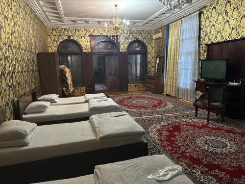 a bedroom with four beds and a television and a room with at May Weather Resort in Bukhara