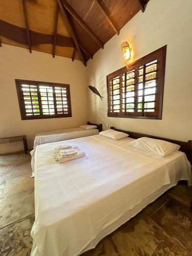 a bedroom with a large white bed with two windows at Pousada Vento do Kite in Barra Grande