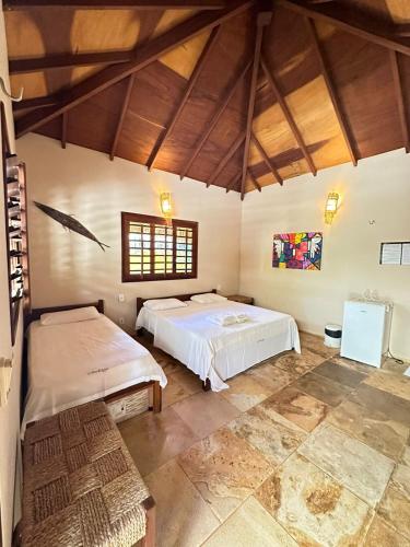 two beds in a room with wooden ceilings at Pousada Vento do Kite in Barra Grande