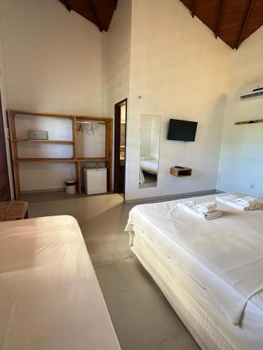 a bedroom with a white bed and a bathroom at Pousada Vento do Kite in Barra Grande