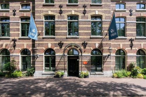 a brick building with two flags in front of it at YAYS Amsterdam Maritime by Numa in Amsterdam