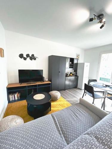 een woonkamer met een bank en een tafel bij Appartement cosy avec terrasse et parking, 4 pers. in Étampes