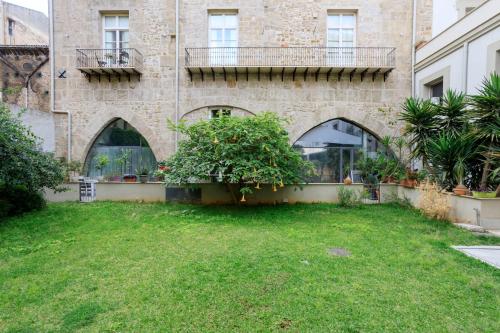 a building with a green yard in front of it at Tomasi Apartment Palermo in Palermo