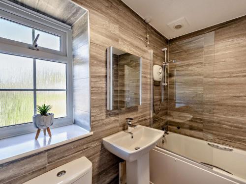 a bathroom with a sink and a toilet and a window at 1 Bed in Westward Ho 46819 in Westward Ho