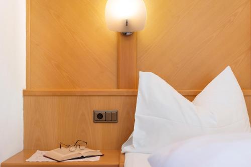 a bed with a lamp and a pair of glasses on a table at Mayr Apartments Eins in Plaus