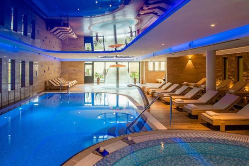 a large swimming pool in a hotel with couches at Hotel Danubia Park in Veliko Gradište