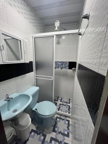 a bathroom with a blue toilet and a sink at Villa del Centro in Paipa