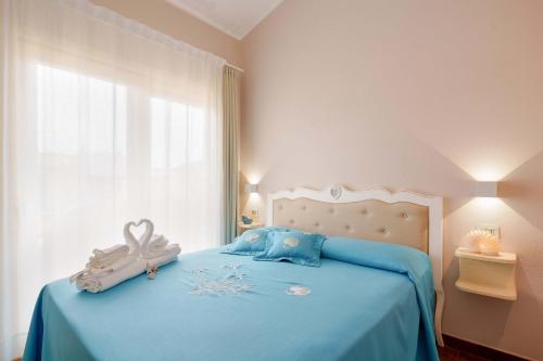a bedroom with a bed with blue sheets and a window at La rosa dei venti in Villasimius