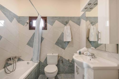a bathroom with a toilet and a sink and a tub at Villa Skala View in Skala Kefalonias