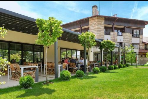 a building with people sitting at tables in a yard at Hotel Danubia Park in Veliko Gradište