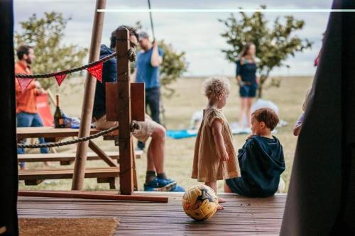 a group of children sitting on a dock with a ball at Safari Tent 5 With Log Burning Tub At Tapnell Farm in Yarmouth
