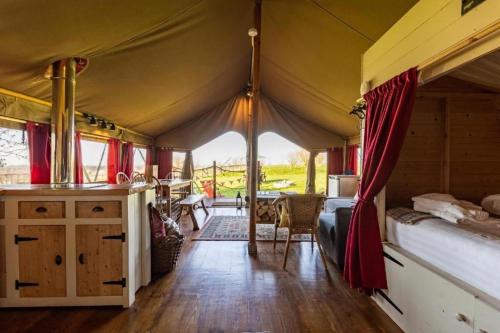 a room with a tent with a bed and a table at Safari Tent 5 With Log Burning Tub At Tapnell Farm in Yarmouth