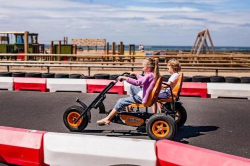 two children riding a toy scooter on the road at Safari Tent 5 With Log Burning Tub At Tapnell Farm in Yarmouth
