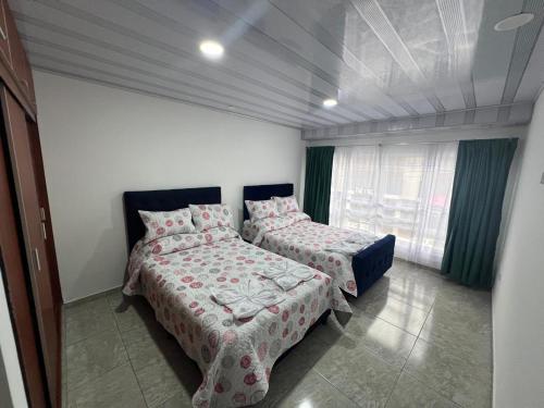 een slaapkamer met twee bedden en een raam bij Villa del Centro in Paipa