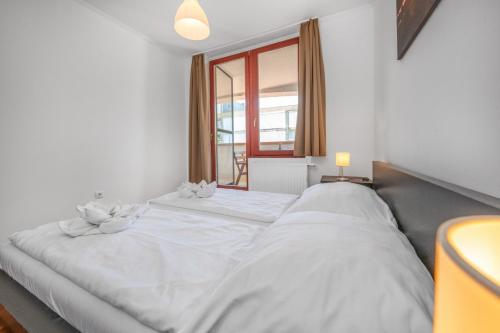 a white bed in a room with a window at Sekli Apartman in Balatonlelle