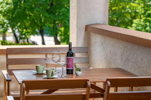 a wooden table with a bottle of wine and two glasses at Sekli Apartman in Balatonlelle