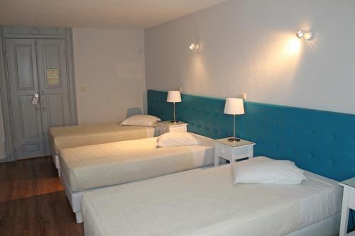 a room with two beds and two lamps on the wall at Hotel Porto Nobre in Porto
