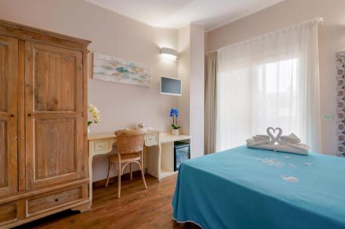 1 dormitorio con cama azul y escritorio en La rosa dei venti, en Villasimius