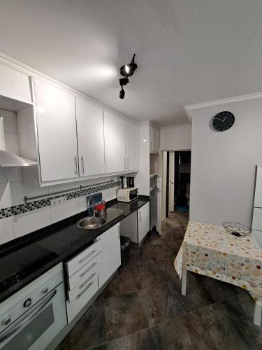 a kitchen with white cabinets and a table in it at Casa Cor de Rosa in Lisbon