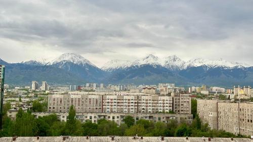 a city with snow capped mountains in the background at Стильная квартира в Алматы in Almaty