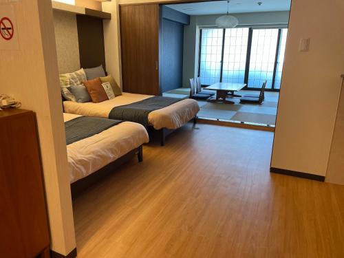 Cette chambre comprend 2 lits et une table. dans l'établissement guest house Sakura, à Osaka