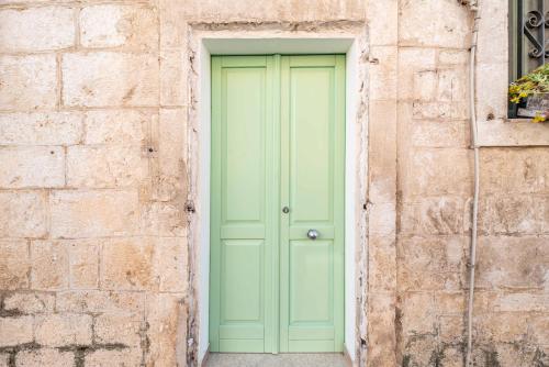 a green door in a brick wall at Vico di Ostuni Apartments by Rentbeat in Ostuni