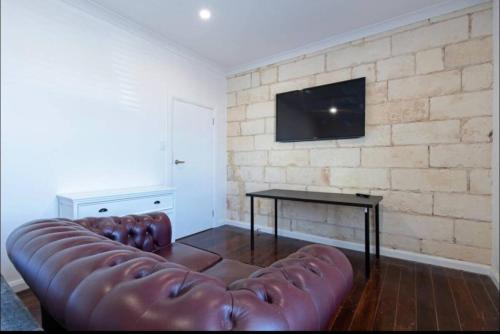a living room with a leather couch and a table at Lovely Beachside Largs Bay unit - free wine in Largs