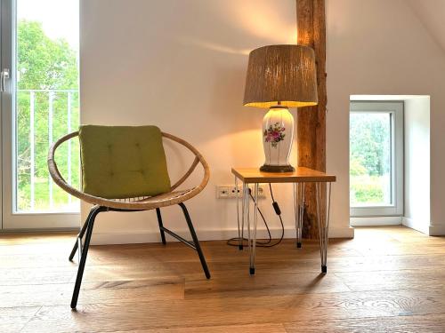 a chair sitting next to a table with a lamp at Fewo Horst_ grün. in Elmenhorst