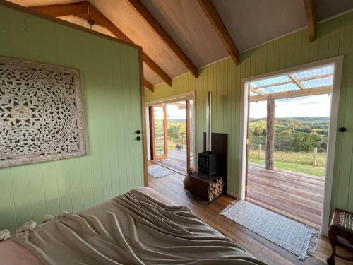 a bedroom with a bed and a door to a deck at Romantic hilltop hideaway - Skyview Cottage in Dairy Flat
