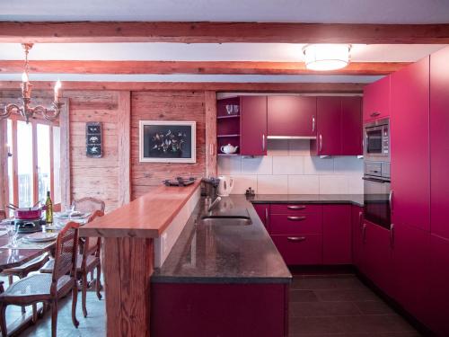cocina con armarios rojos y mesa de comedor en Apartment Ambassadeur by Interhome, en Villars-sur-Ollon