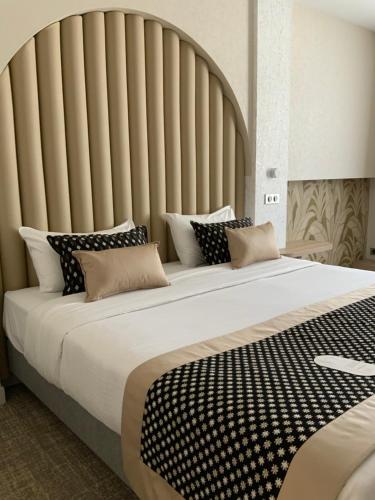 a large bed with black and white pillows on it at Le Renaissance in Mont-de-Marsan