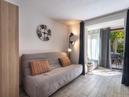 un salon avec un canapé et une horloge au mur dans l'établissement Studio Les Mimosas Bleus-4 by Interhome, à Bormes-les-Mimosas
