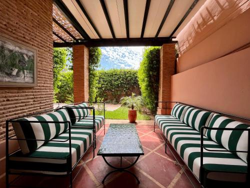 - une terrasse couverte avec des canapés et une table dans l'établissement Villa Sofia - Golf Amelkis Marrakech, à Marrakech