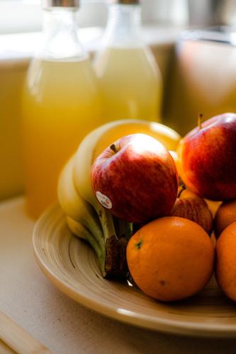 ein Teller mit Äpfeln, Orangen und Bananen sowie Flaschen mit Saft in der Unterkunft Green Coast Surf House in Espinho