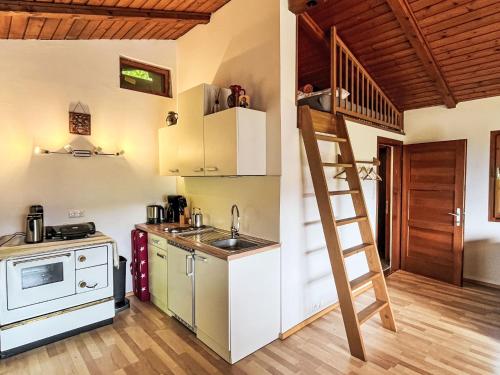 a kitchen with a staircase leading up to a loft at Holiday Home Häuschen am Waldrand by Interhome in Annenheim