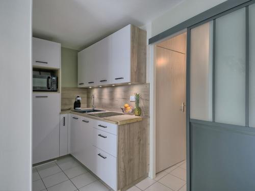 une cuisine avec des armoires blanches et un évier dans l'établissement Apartment Les Voiles de La Baule by Interhome, au Pouliguen