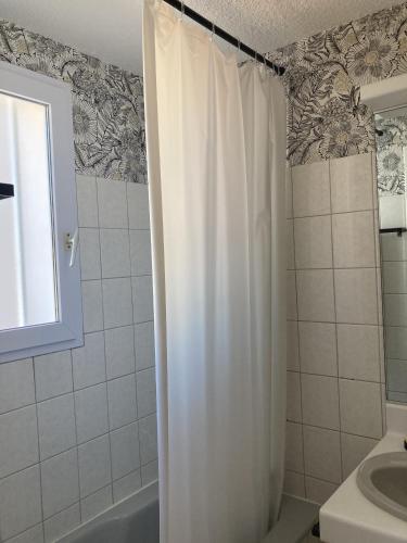 une salle de bain avec un rideau de douche et un lavabo dans l'établissement Le doux refuge aperçu mer, à Les Sables-dʼOlonne