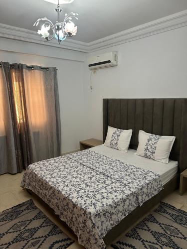 um quarto com uma cama e um lustre em Coquette appart de plage em Hammam Sousse