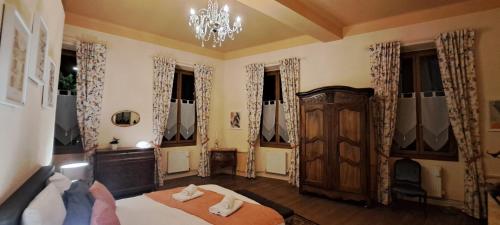 a bedroom with a bed and a chandelier and windows at La Vernassonne in Alzonne