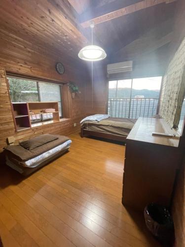 a large room with two beds and a table in it at ゲストハウス なないろ in Naze