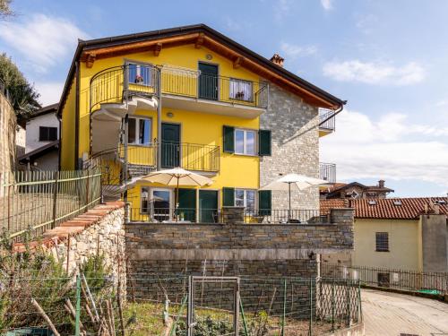 a yellow house with umbrellas in front of it at Apartment Raggio di Sole Apartment A and B by Interhome in Consiglio di Rumo
