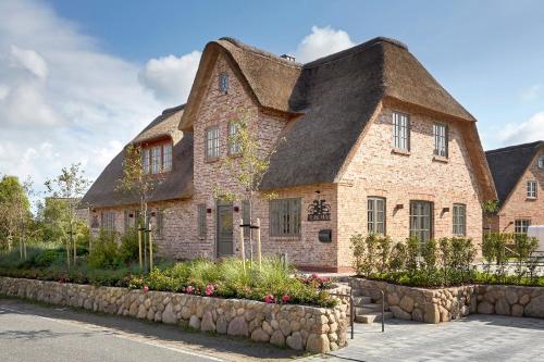 a large stone house with a thatched roof at Marschkajüte in Oldsum