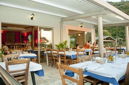 un restaurant avec des tables et des chaises blanches et des personnes qui y sont assises dans l'établissement Hotel Elina, à Perdika