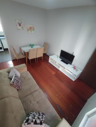 a living room with a couch and a table with a tv at Apto com suíte, garagem, localização privilegiada in Belo Horizonte