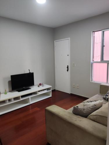 a living room with a couch and a flat screen tv at Apto com suíte, garagem, localização privilegiada in Belo Horizonte