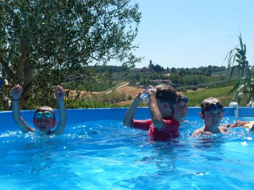 3 bambini nuotano in una piscina di La Rocca Chianti Hospitality a Tavarnelle in Val di Pesa
