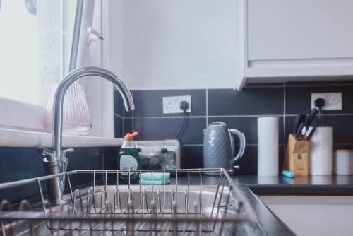 a kitchen sink with a dish rack in a kitchen at Modern And Vibrantly Designed Apartment in Motherwell
