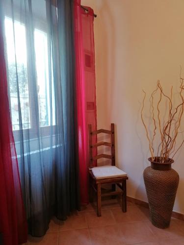 a chair in a room with a window and a plant at appartamento Papaveri di Casa Mosaico in Volterra