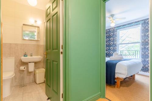 a bathroom with a green door and a bed and a sink at Bright 3 Bedroom House Near King's Cross StPancras in London