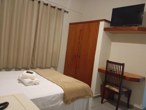 a bedroom with a bed and a cabinet with a television at Mariachis Hotel in Passos